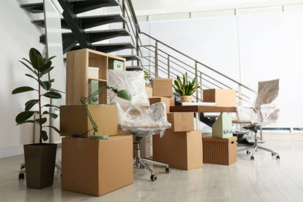 Cardboard boxes and furniture near stairs in office. Moving day